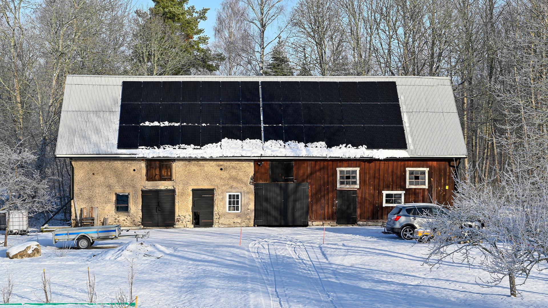 Solcellspaneler på ett tak med snö som rasat ner från panelerna